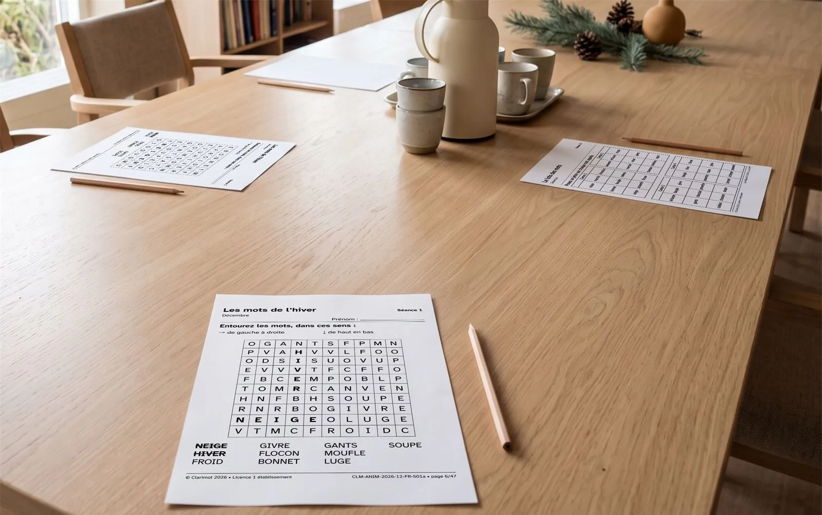 Table d'une salle d'activités avec des pages de jeux en gros caractères et des crayons, décor d'hiver.
